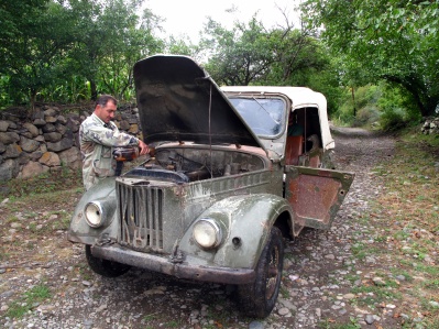 A man fixing his classic car near the start of the trail